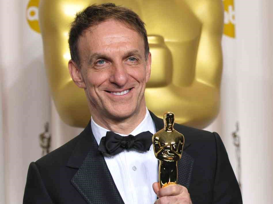 Mychael Danna smiling, wearing a tuxedo and holding his Academy Award